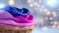 Colorful folded fabrics in shades of blue and pink stacked in woven basket with soft bokeh lights, suitable for textile, fashion, and home decor design projects.