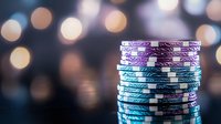 Stack of blue and purple poker chips on dark background with soft bokeh lights, creating atmospheric casino gaming ambiance. Suitable for gambling and entertainment concepts.
