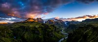 Dramatic mountain landscape with winding river valley at sunset, featuring rugged peaks under colorful sky with clouds, suitable for travel and nature backgrounds.