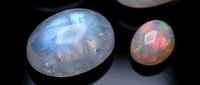 Opal gemstones with rainbow fire displaying natural iridescent colors and optical phenomena on dark surface for jewelry design and luxury accessories.