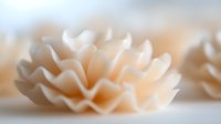 Delicate cream-colored flower petals arranged in soft layers create gentle waves and folds against blurred neutral background, showcasing elegant natural forms.