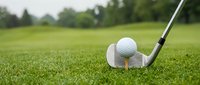 Golf club and ball on green grass course ready for tee shot with blurred fairway background for sports and recreation concepts.