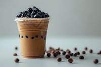 Refreshing bubble tea with brown tapioca pearls and blueberry topping in plastic cup on light background, perfect for beverage menu or cafe promotion.