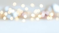 Soft blurred bokeh lights background with warm golden and white circular light spots creating dreamy atmospheric effect for holiday celebrations and events.