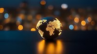 Glowing golden world map sphere floating over reflective surface against blurred city lights background creates magical evening atmosphere.