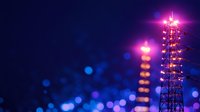 Illuminated telecommunications tower with pink and purple lights against dark night sky, glowing bokeh effect creates dreamy atmosphere. Modern connectivity concept.
