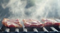 Raw meat steaks sizzling on hot barbecue grill with rising smoke creating atmospheric cooking scene, close-up view showing juicy texture and grilling process.
