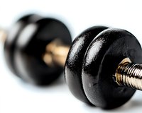 Black metal dumbbell with chrome handle on white background, close-up macro shot showing texture and detail. Fitness and strength training equipment.