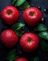 Fresh red apples with water drops on dark background and green leaves. Macro shot of wet ripe fruit with natural lighting for food photography and design.
