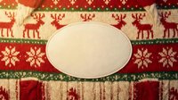 Blank white oval label on festive knit fabric with reindeer and snowflake patterns, perfect for holiday gift tags, product labels, and seasonal packaging design projects.