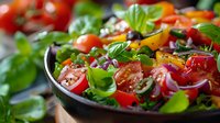 Fresh garden salad with cherry tomatoes, red onions, bell peppers and basil leaves in dark bowl, macro food photography with selective focus.