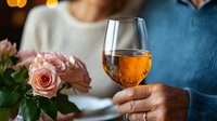 Romantic evening with rose wine glass, pink roses on table. Couple enjoying intimate dinner date at restaurant with soft bokeh lighting in background.