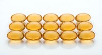 Golden omega-3 fish oil capsules arranged in neat rows on white background. Health supplement pills for wellness and nutrition support.