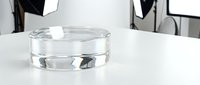 Clear glass bowl with water on white table in modern studio setting with professional lighting equipment in background.