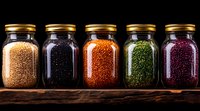 Colorful assortment of dried lentils and beans in glass jars with golden lids on rustic wooden surface against dark background, dramatic food photography.