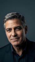 Professional mature businessman with gray hair smiling confidently in dark suit against blue background for corporate headshot and business portrait.