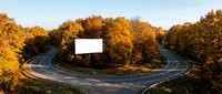 Curved highway interchange surrounded by vibrant autumn foliage at golden hour. Scenic road infrastructure with warm fall colors and dramatic lighting.
