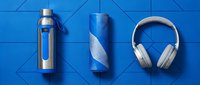 Portable water bottle, wireless speaker, and over-ear headphones arranged on blue geometric background for tech lifestyle and gadget marketing campaigns.
