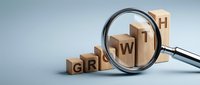 Wooden blocks spelling GROWTH under magnifying glass representing business development, success analysis, and strategic planning for corporate expansion.
