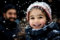 Joyful young child wearing winter coat and knit hat plays in falling snow, capturing pure happiness and seasonal magic with authentic smile and rosy cheeks.