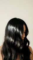 Young woman with glossy black wavy hair in profile view against neutral background for beauty and haircare advertising campaigns.