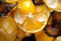Fresh lemon slices with ice cubes in golden light, macro close up view showing citrus fruit texture and translucent details for beverage and food photography.