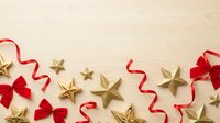 Festive holiday flat lay with red ribbon bows and gold stars on wooden surface, perfect for Christmas greeting cards, seasonal marketing, and holiday design projects.