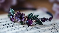 Elegant floral headband with purple flowers and green leaves resting on sheet music, bridal hair accessory for weddings and special occasions.