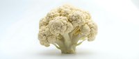 Whole raw cauliflower head with dense florets isolated on white background, suitable for food, nutrition, cooking, and healthy eating content.