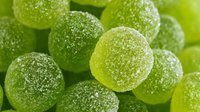 Green sugar-coated jelly candies in close-up view, showing texture and sweetness for food photography, confectionery advertising, and culinary content.