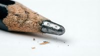Sharpened wooden pencil with graphite tip and shavings on white surface, isolated for design and educational use.