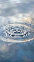 Water ripples create concentric circles on calm surface with cloudy sky reflection, symbolizing tranquility, meditation, and peaceful moments in nature.