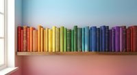 Rainbow colored books arranged in spectrum order on a wooden shelf against a pastel gradient wall with soft natural light.
