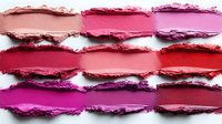 Crushed and smeared lipstick samples in various shades of pink, red, and purple arranged in rows on white background showing texture and pigment intensity.