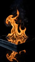 Dramatic orange flames dancing from reflective surface against dark background with swirling smoke and sparks creating powerful energy and heat visualization.