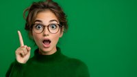 Young Caucasian woman in glasses and green sweater showing eureka moment with raised finger, expressing excitement and sudden idea against green background.