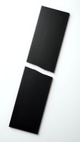 Black exclamation mark symbol made from paper cutouts on white background isolated for graphic design and typography projects.