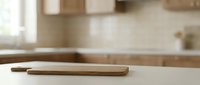 Wooden cutting board on kitchen counter with blurred cabinetry and appliances in background, suitable for food preparation and culinary content.