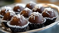 Dark chocolate truffles with coconut flakes served in black paper cups on silver platter. Homemade gourmet confectionery dessert with rich ganache filling.