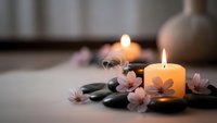 Spa wellness scene with burning candles, hot stones and cherry blossoms creating peaceful atmosphere for relaxation and meditation therapy treatments.