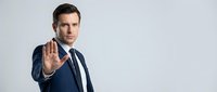 Professional businessman in navy suit making stop gesture with hand raised, serious expression, corporate leadership and authority concept for business presentations.