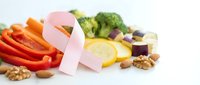 Pink ribbon symbol with colorful healthy foods including vegetables, fruits and nuts on white background for cancer awareness and nutrition support.