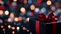 Black glittery gift box with elegant red satin bow against blurred bokeh lights background creating magical holiday atmosphere for celebrations and special occasions.