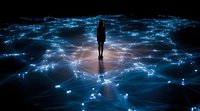 Silhouette of person standing on glowing digital network surface with interconnected nodes and light trails spreading across dark background, concept of artificial intelligence.