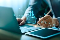 Businessman using smartphone and laptop with digital download icons and data analytics overlay in modern office environment for technology concepts.