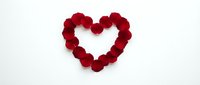 Red rose petals arranged in a heart shape on a white background, symbolizing love and romance for Valentine's Day greeting cards.