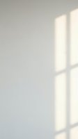 Minimalist white wall with soft natural window light casting geometric shadows, creating clean lines and subtle depth for modern design backgrounds.