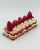 Elegant rectangular pastry with fresh strawberries and whipped cream rosettes layered between crisp tart shells, dusted with powdered sugar on neutral background.