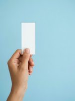 Hand holding blank white rectangular card against light blue background for branding, marketing, and promotional mockup purposes.