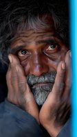 Emotional portrait of mature South Asian man with gray beard and intense gaze holding hands to face, dramatic lighting highlights expressive eyes and weathered features.